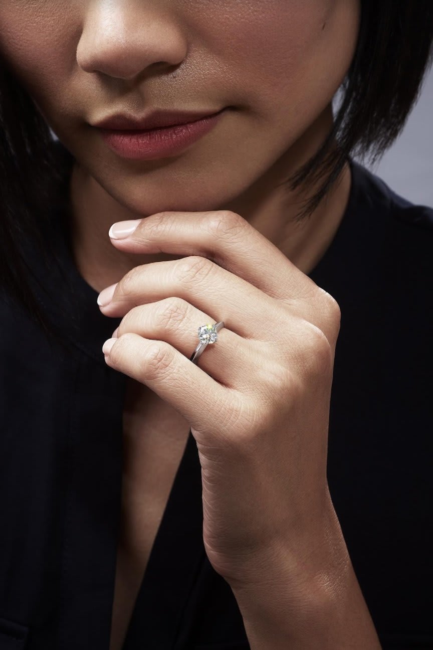 A classic solitaire engagement ring with a brilliant-cut diamond on a hand