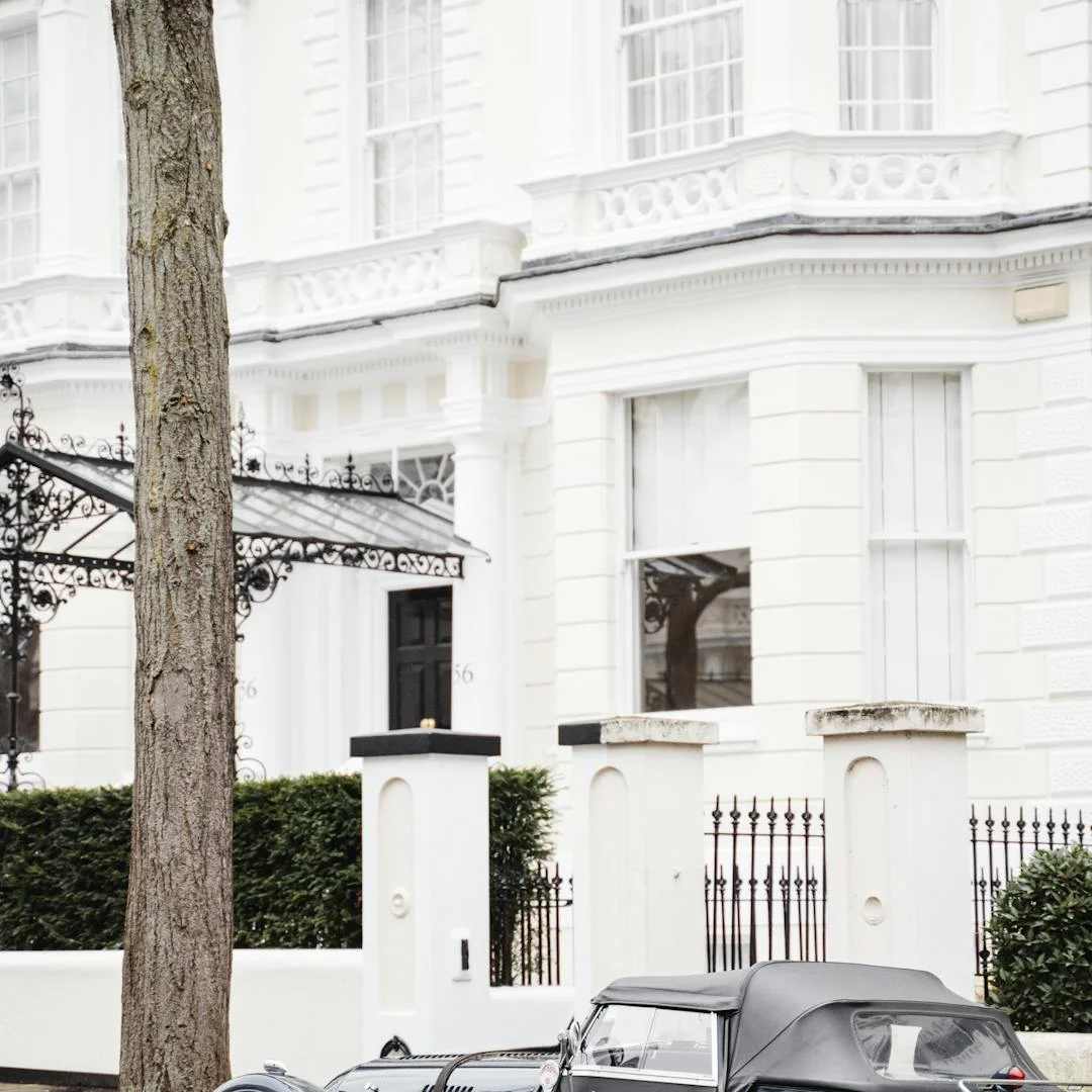 Elegant white townhouses and a classic car line a street in London's affluent Mayfair district, exemplifying ultra-luxury real estate