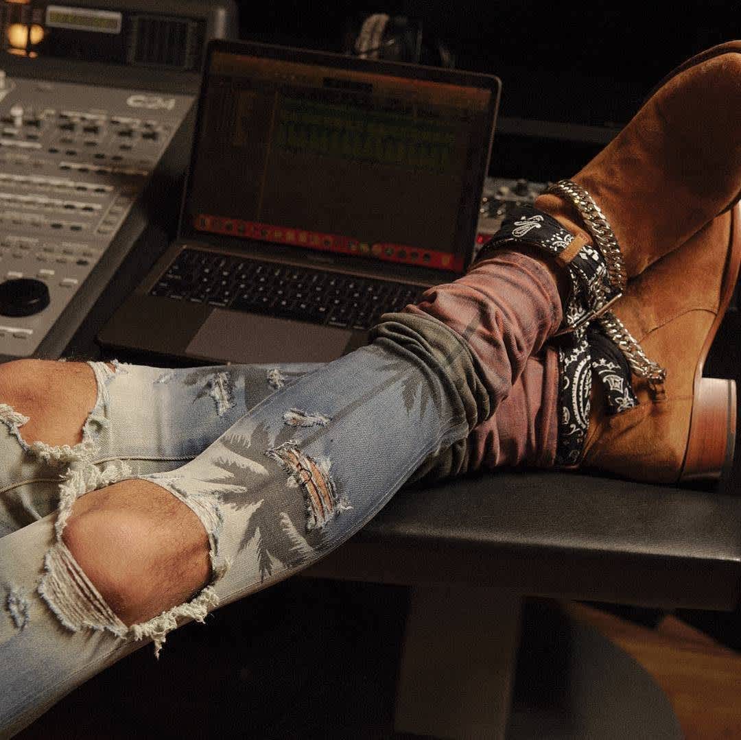 Distressed denim paired with suede boots and a bandana accessory, showcasing a blend of casual and elevated streetwear style
