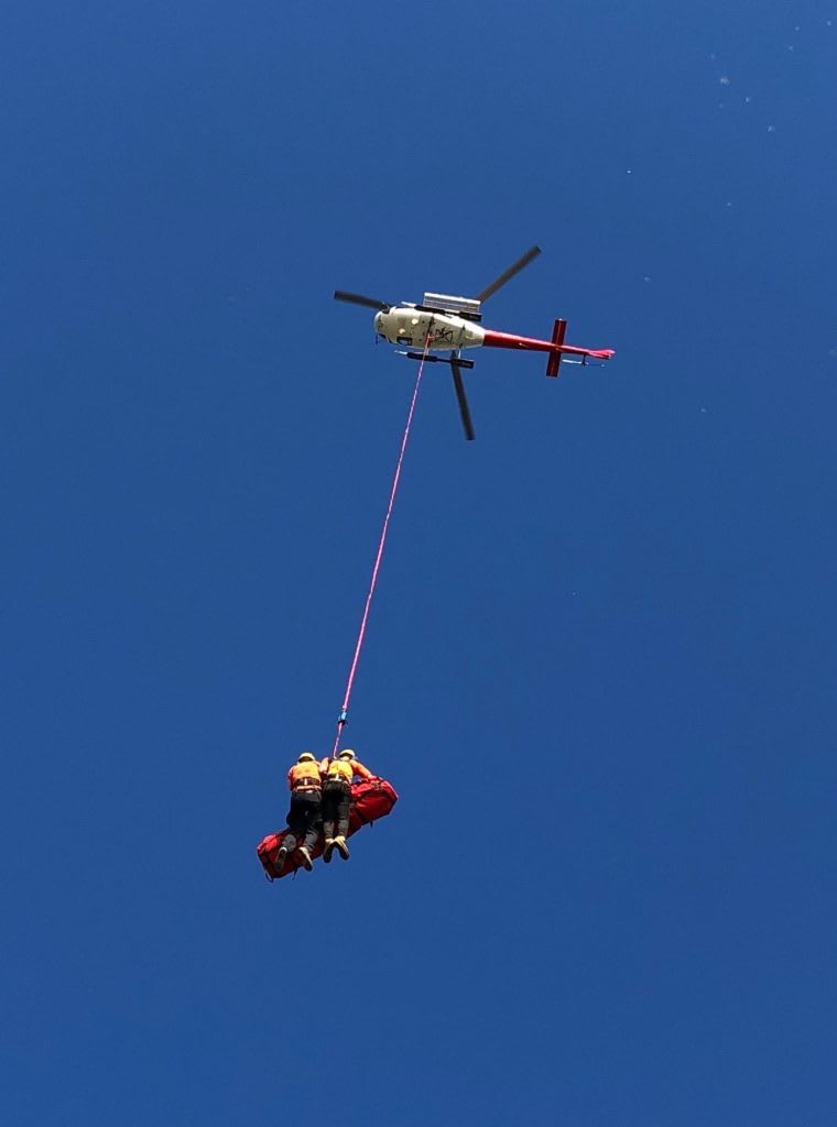Mountain rescue team members being airlifted by helicopter during a training or real rescue operation
