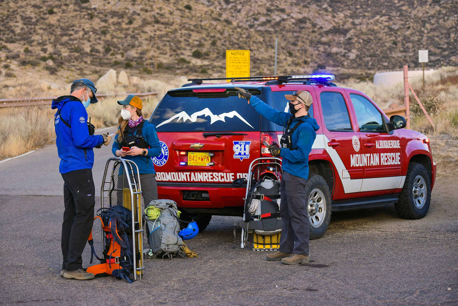 Mountain rescue volunteers prepare for wilderness emergency response near their rescue vehicle