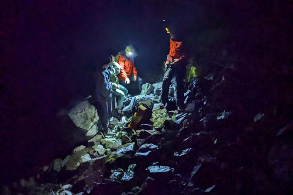Mountain rescue team assisting a lost hiker during a nighttime operation on rocky terrain