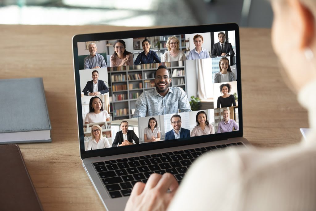 A diverse group of remote professionals engaged in a virtual team meeting on a laptop screen.