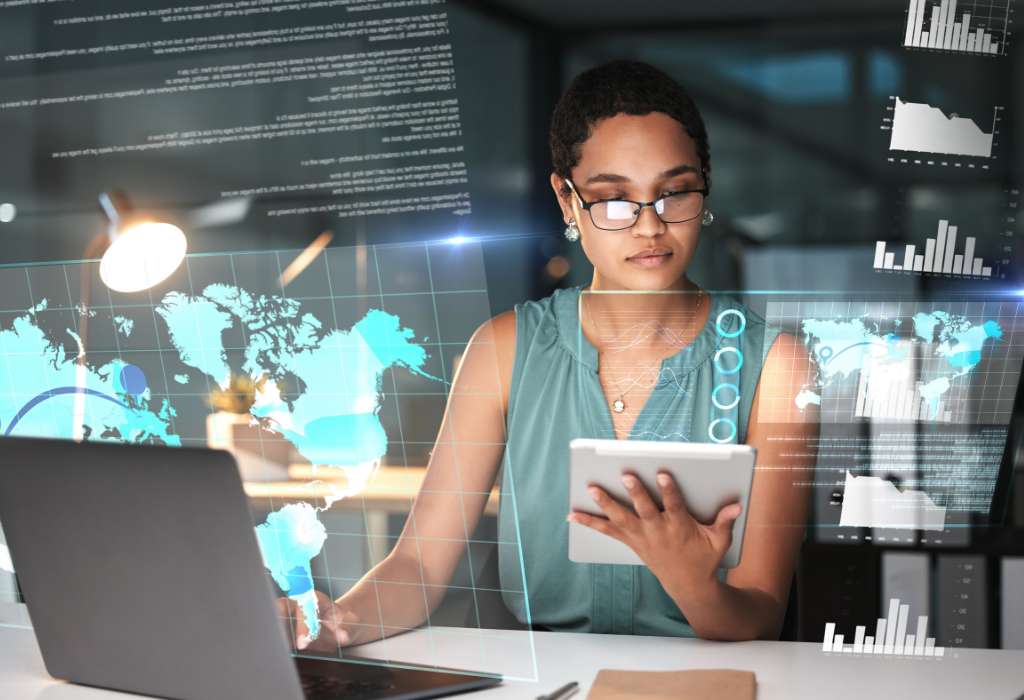 A professional woman using digital tools and data visualizations to analyze global staffing and business solutions in a modern tech environment.
