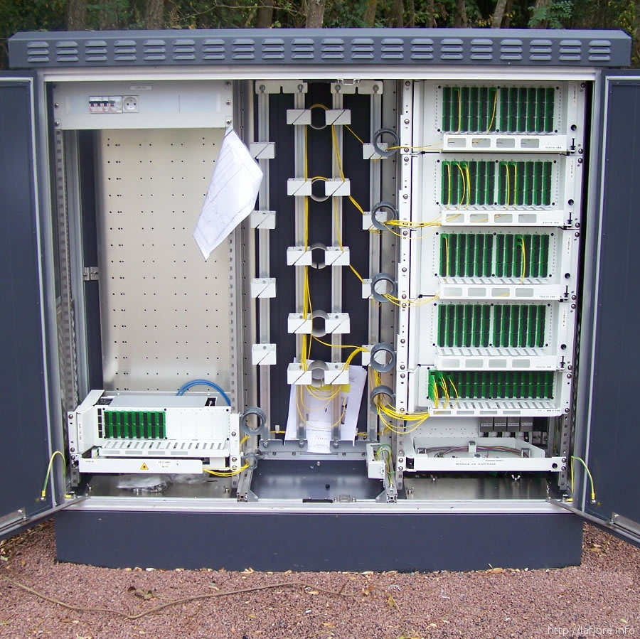 Open fiber optic street cabinet (PMZ/PMI) showing fiber splice trays and organized fiber cables for network distribution