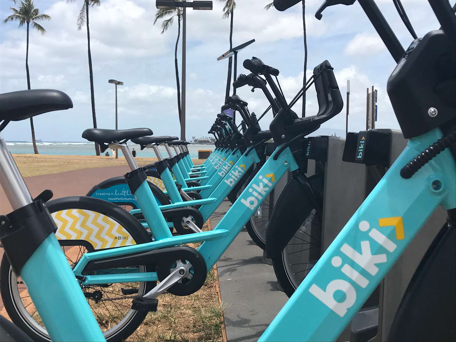 Biki rental bikes lined up at a docking station in Honolulu, offering a convenient alternative to car rentals in Oahu