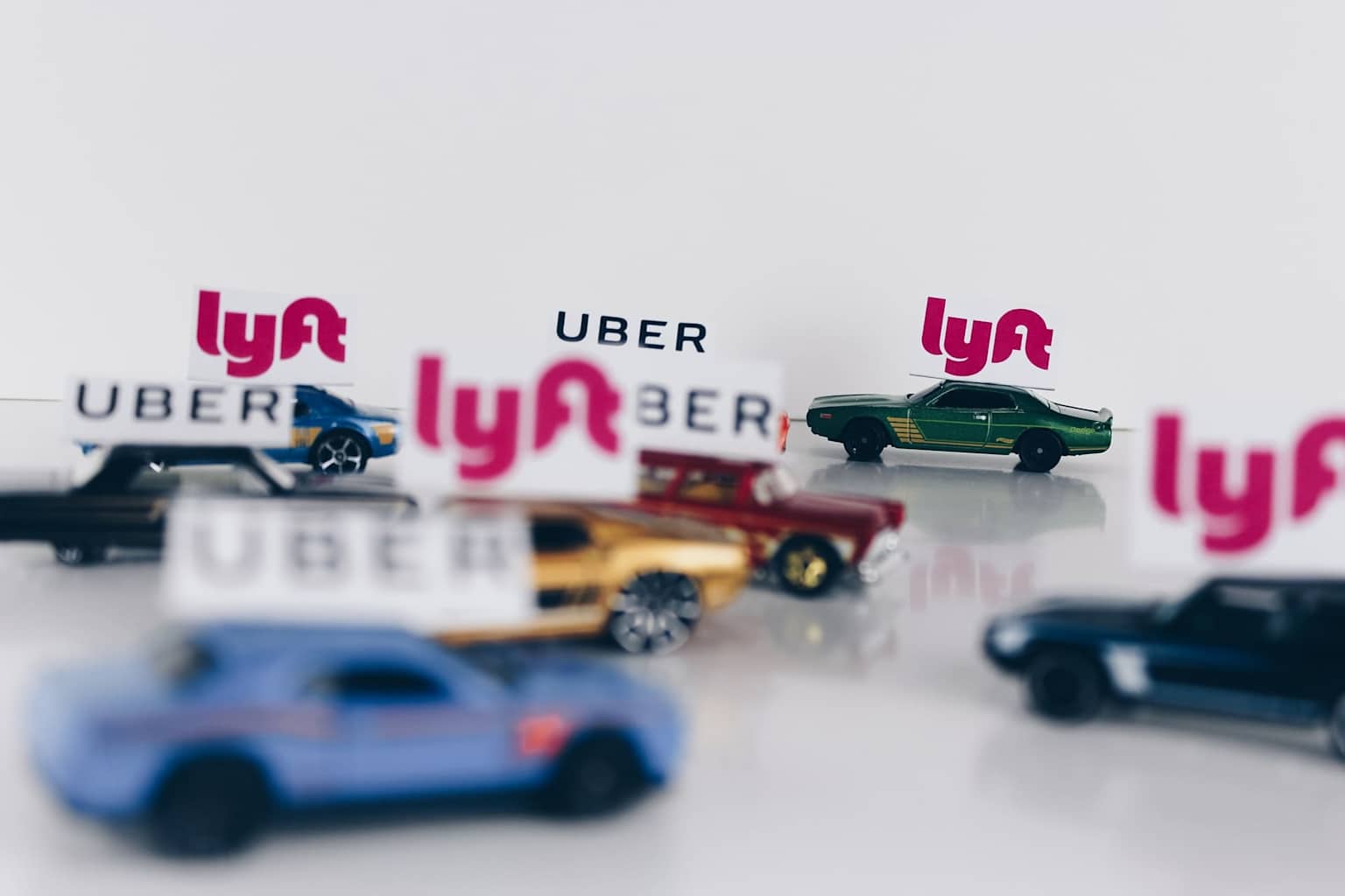 Toy cars labeled with Uber and Lyft logos symbolize rideshare competition in Hawaii's tourism market
