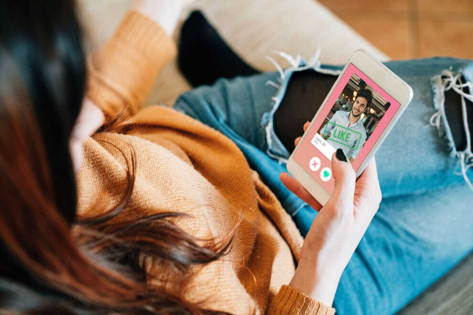 A woman using a dating app on her smartphone, swiping right to like a profile, illustrating the concept of 'love at first swipe.'