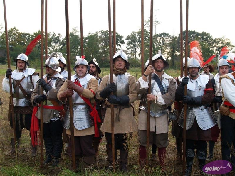 Group of historical reenactors dressed in authentic 17th-century military uniforms holding pikes during an outdoor event