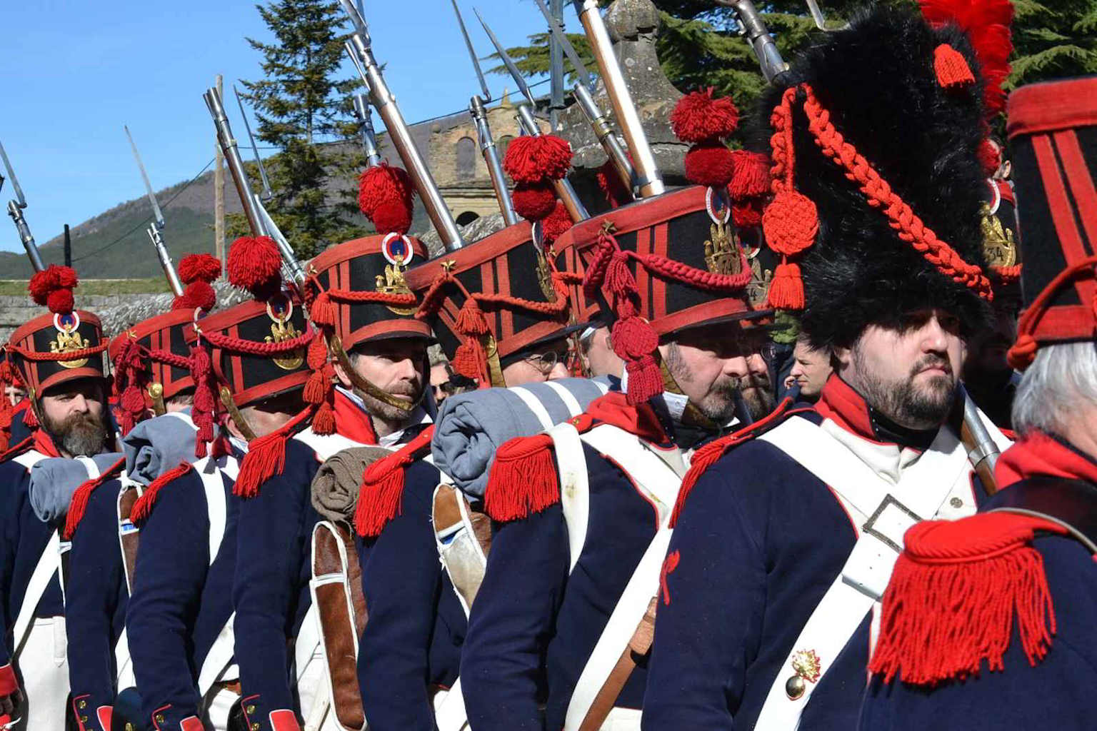 Group of Napoleonic-era historical reenactors in authentic military uniforms during an outdoor event