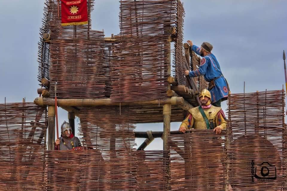 Historical reenactors in authentic period costumes on a rustic wooden fort, embodying the immersive experience of living history