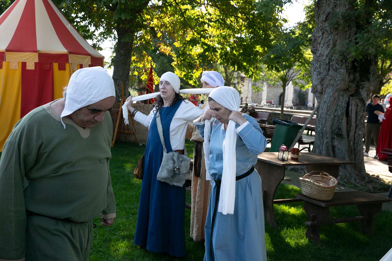 Grupo de recreadores históricos vestidos con trajes medievales en un evento al aire libre, mostrando la autenticidad y el espíritu comunitario de la recreación histórica