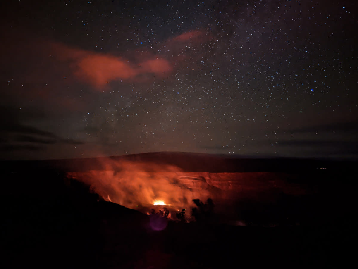 Nighttime view of Kilauea volcano's glowing lava crater under a star-filled sky on Hawaii's Big Island