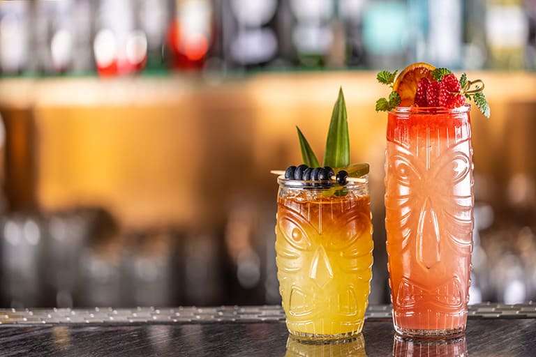 Tiki-style cocktails with fresh fruit garnishes at a Hawaiian bar showcasing vibrant local drink culture