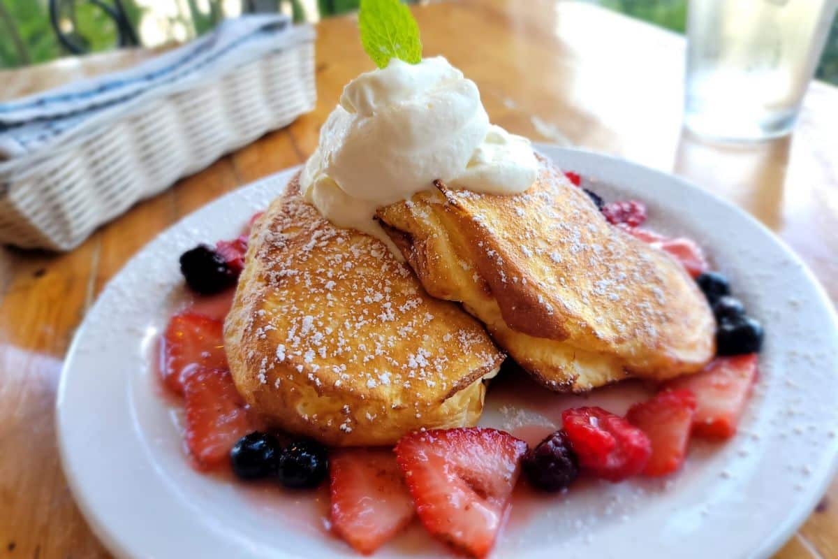 Local Hawaiian breakfast featuring fluffy pancakes with fresh berries and whipped cream at a cozy cafe