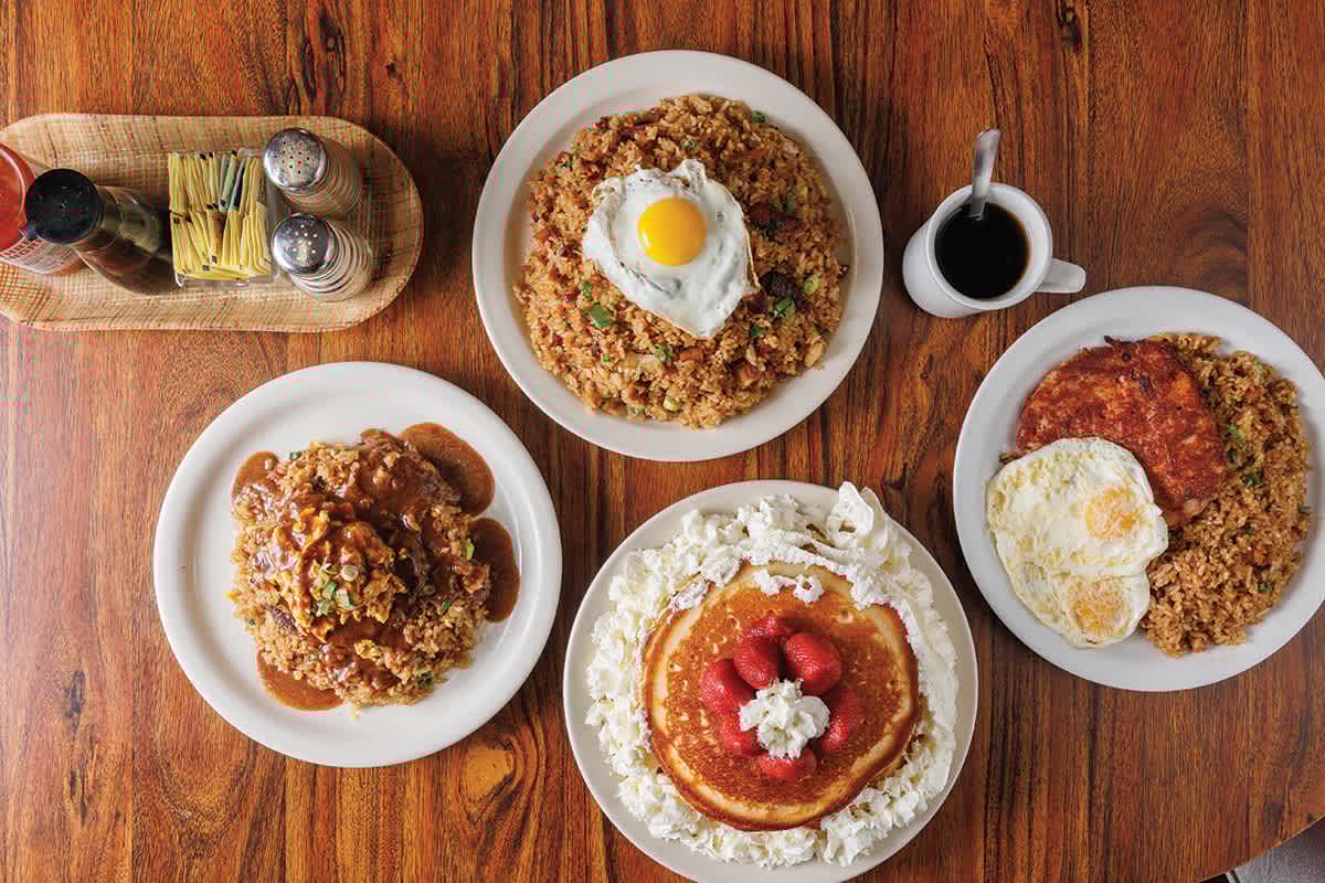 Local Hawaiian breakfast dishes including fried rice with eggs, Portuguese sausage, and pancakes with strawberries at a family-run coffee shop