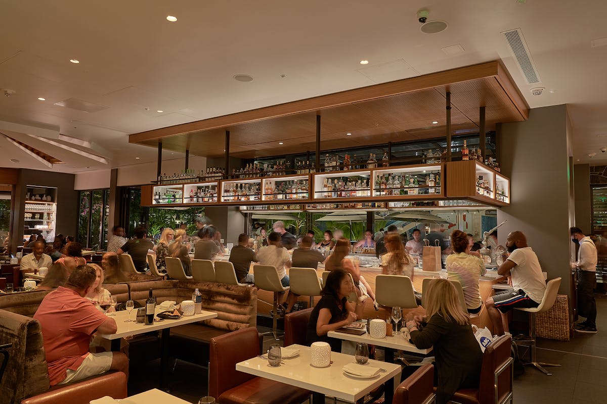 Interior of STRIPSTEAK by Michael Mina in Waikiki showcasing a modern steakhouse ambiance with a lively bar and elegant seating