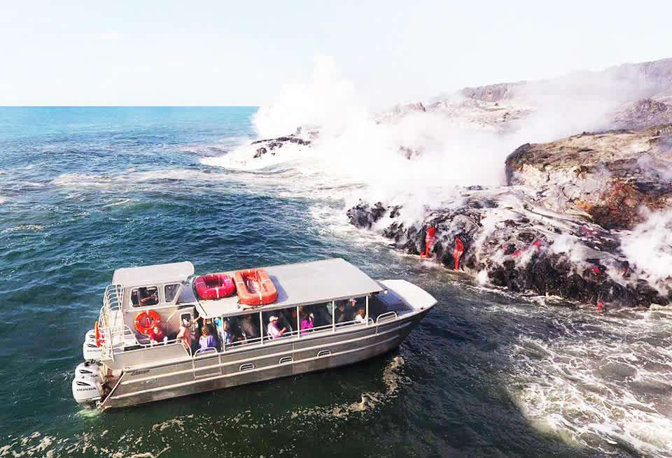 Tourists experience a thrilling lava boat tour in Hawaii, witnessing molten lava meet the ocean amidst rising steam and volcanic landscape