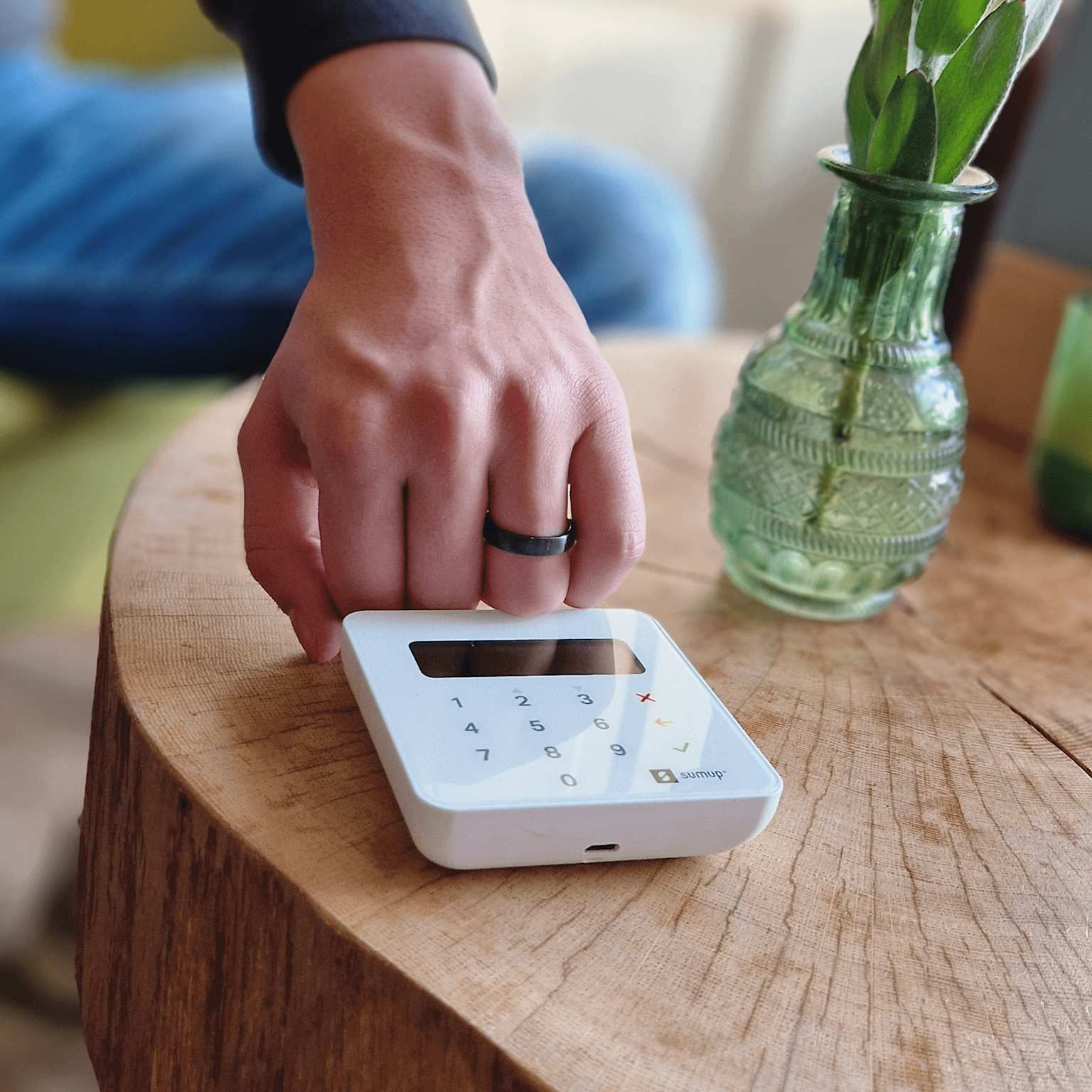 A hand wearing a black payment ring performing a contactless payment on a small terminal device