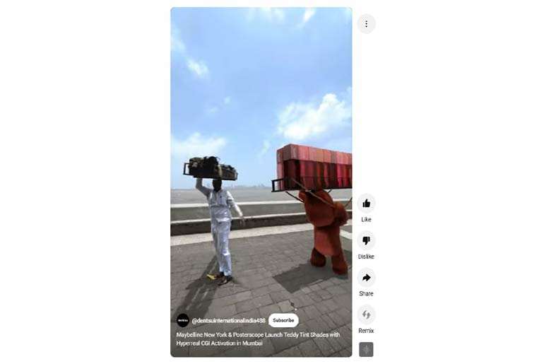 A Mumbai dabbawala walks next to Maybelline's CGI teddy bear mascot near the sea, highlighting the campaign's blend of local culture and digital imagery