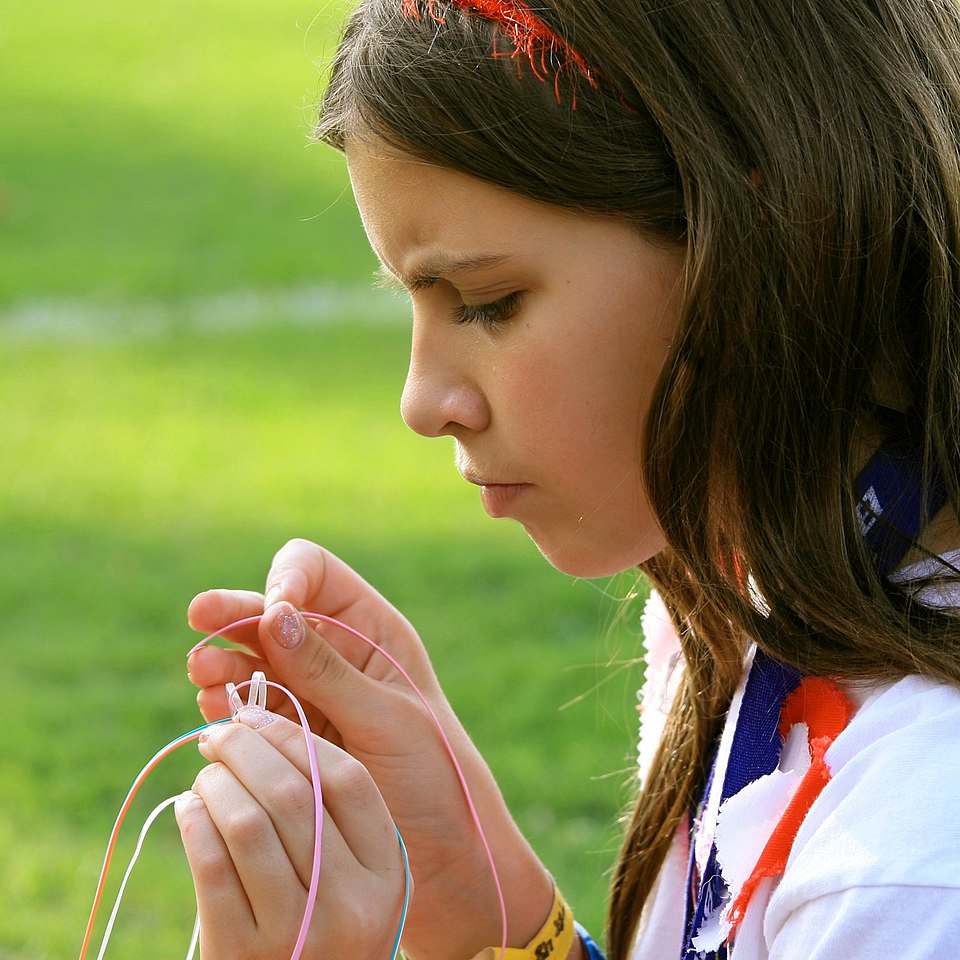Person focused on threading colorful strings, exemplifying a flow state and deep concentration during a creative task
