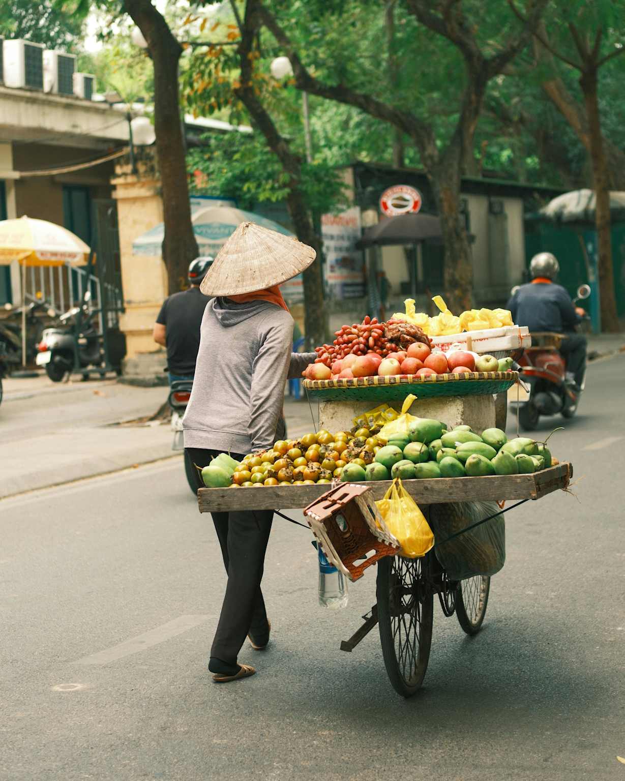 A street vendor in Hanoi with a bicycle cart full of fresh fruits, illustrating local street food culture