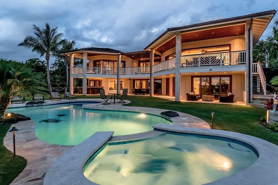 Luxury Hawaii Kai home featuring a large pool and spacious balconies set against a dramatic twilight sky showing typical affluence in the neighborhood