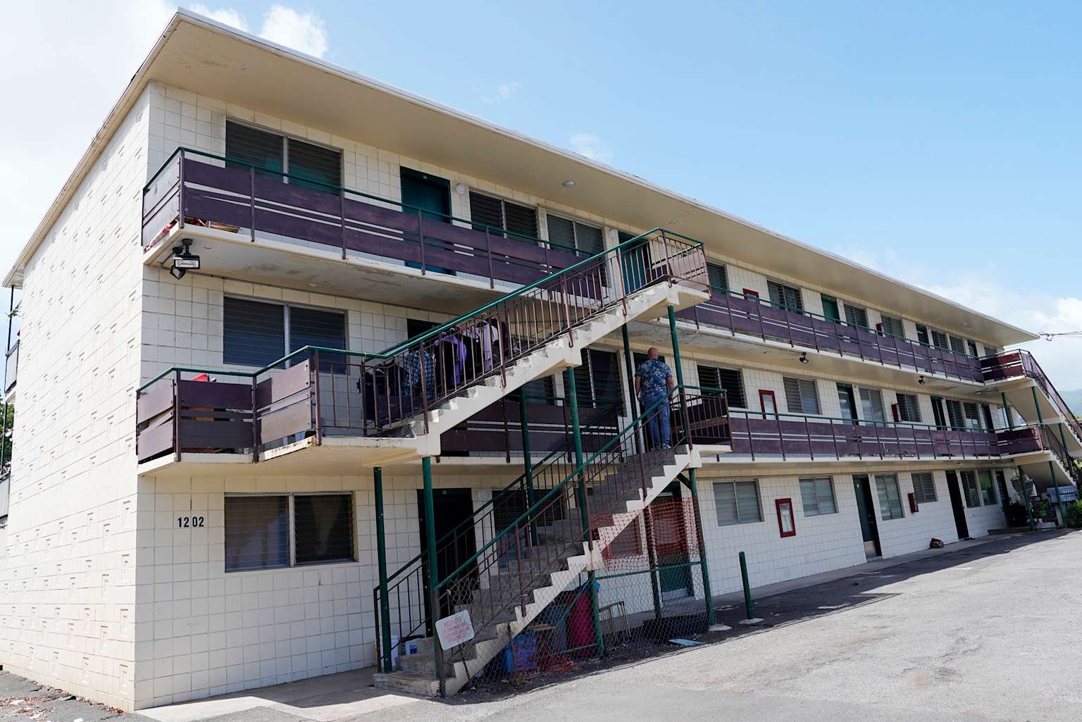 Modest multi-story apartment building with exterior stairway typical of affordable housing in Honolulu's Kalihi neighborhood