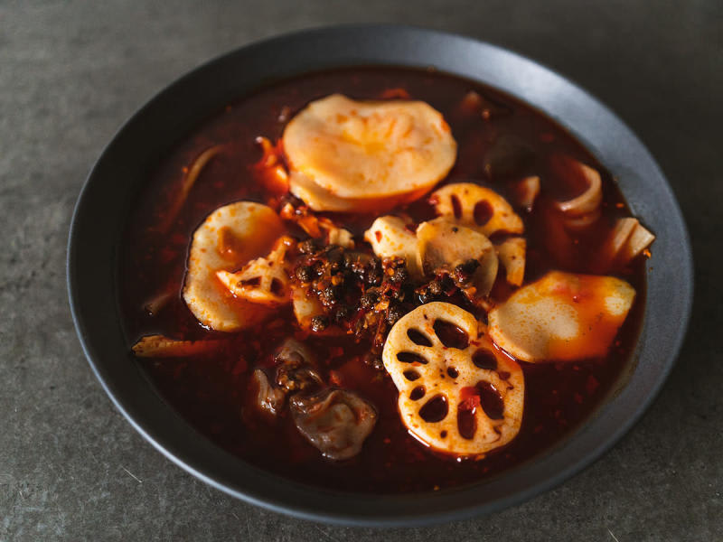 A spicy Asian soup with lotus root and tofu slices from an Oakland Chinatown restaurant, showcasing authentic flavors
