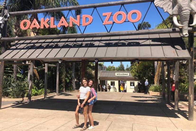Entrance to the Oakland Zoo featuring a large wooden sign and an elephant sculpture under a sunny sky