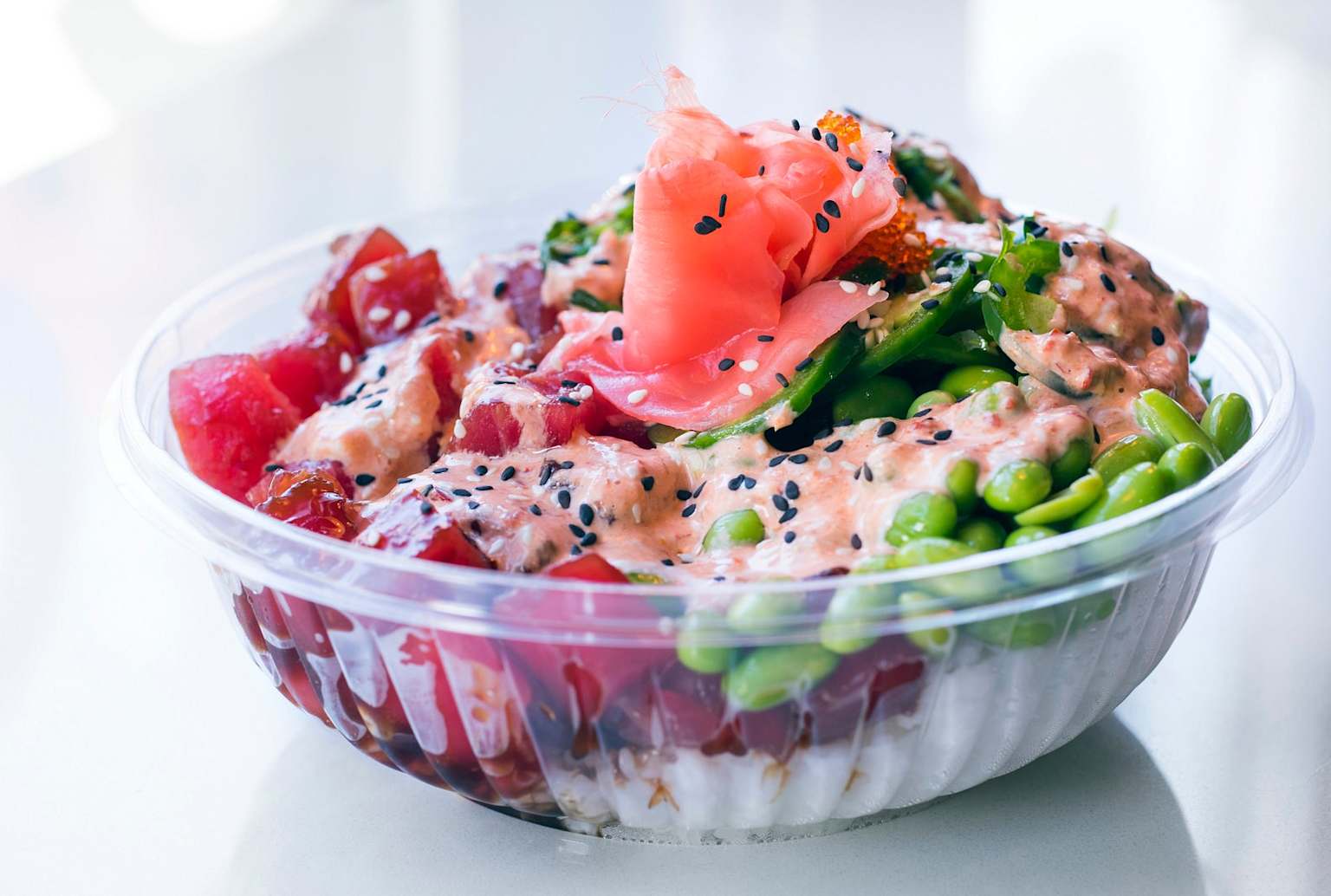 A fresh poke bowl with tuna, edamame, pickled ginger, and sesame seeds showcasing typical ingredients of a Hawaiian poke dish
