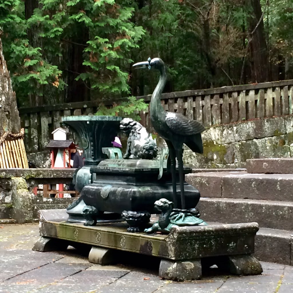 Bronze statues of a crane and a turtle at a traditional Japanese shrine, symbolizing longevity and endurance