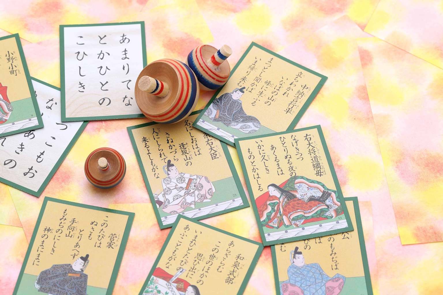 Traditional Japanese karuta cards and spinning tops illustrate the cultural context of Japanese children's games like 'かごめかごめ.'