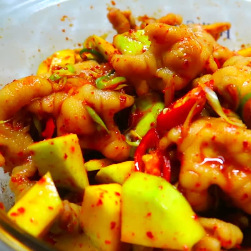 Chicken feet in spicy Thai-style sauce with chili, green onions, and green mango pieces
