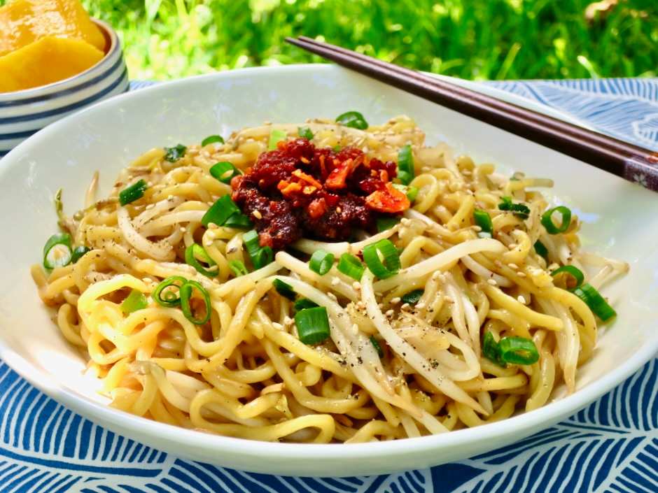Sam Sato's dry mein noodles topped with chili crisp and fresh green onions, showcasing a beloved Maui local dish