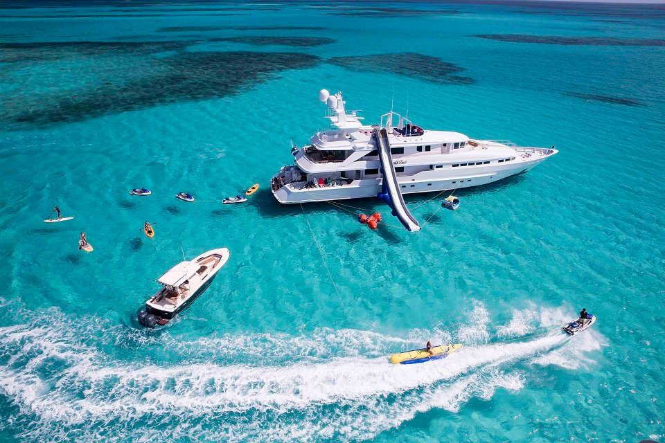 Luxury white yacht with water slide and water sports in clear Caribbean waters illustrating a tropical yacht charter experience