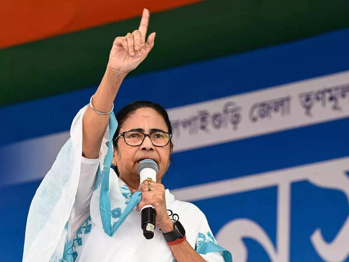 A woman speaker in a white saree with blue patterns addresses a political gathering in West Bengal, raising her finger for emphasis
