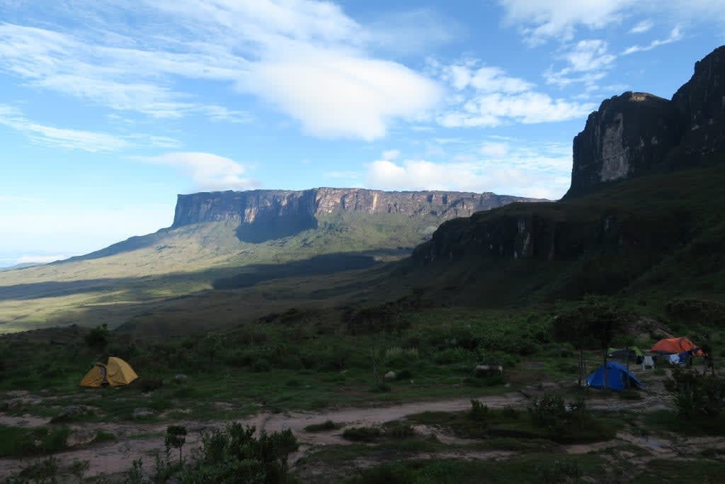 Camp base at Mount Roraima with tents set against the iconic flat-topped mountain under a bright sky
