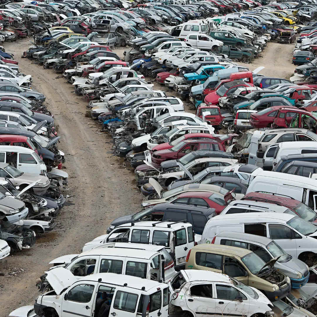 A large car scrapyard with numerous old and dismantled vehicles arranged in rows, illustrating the concept of automotive salvage yards