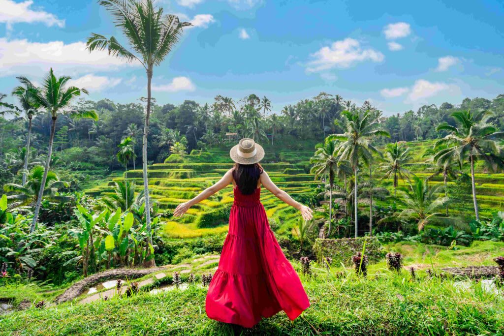 A woman in a red dress enjoying the peaceful rice terraces and tropical landscape, embodying the spirit of slow travel in an exotic destination