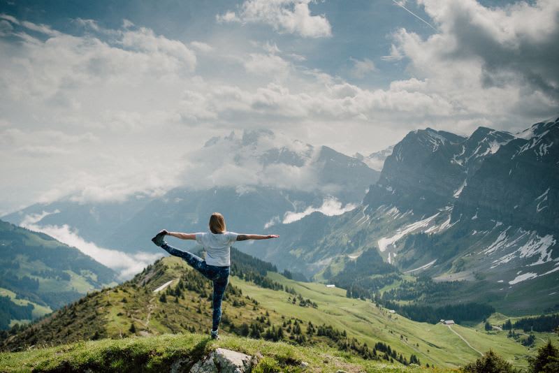 Person practicing yoga on a mountain hilltop, embracing mindfulness and nature in a peaceful setting