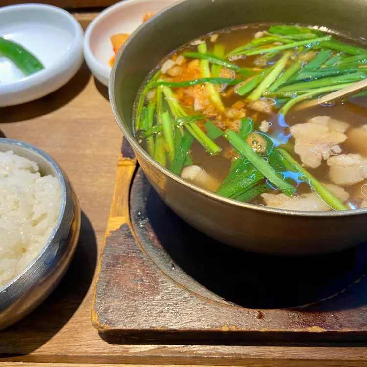 A bowl of traditional Korean pork soup (Yangsan Gukbap) with rice and side dishes at a Busan station eatery.