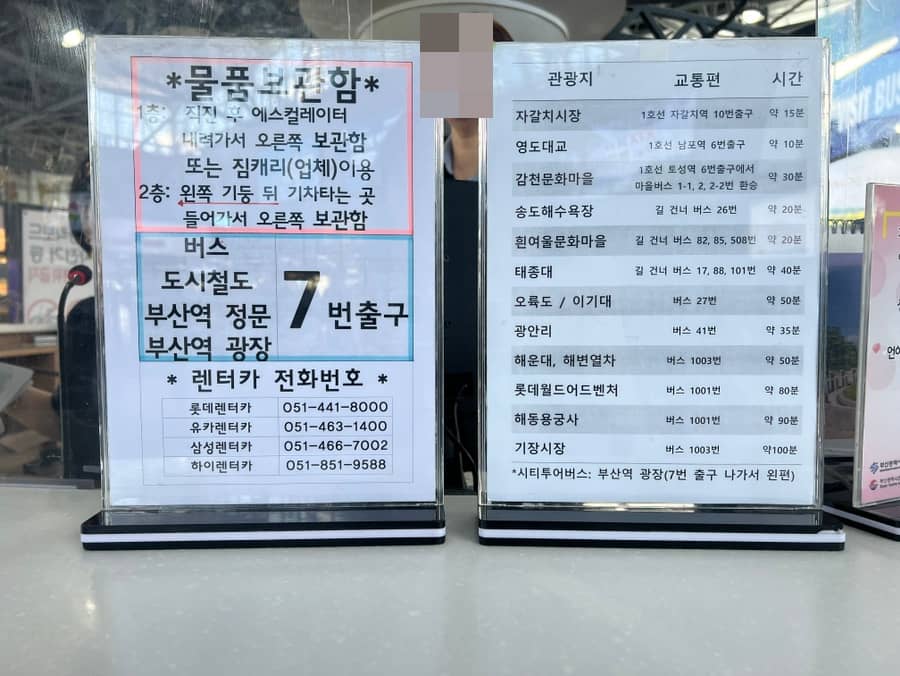 Information signs at Busan Station detailing luggage storage locations, transportation exits, and travel times to nearby destinations by train or bus.