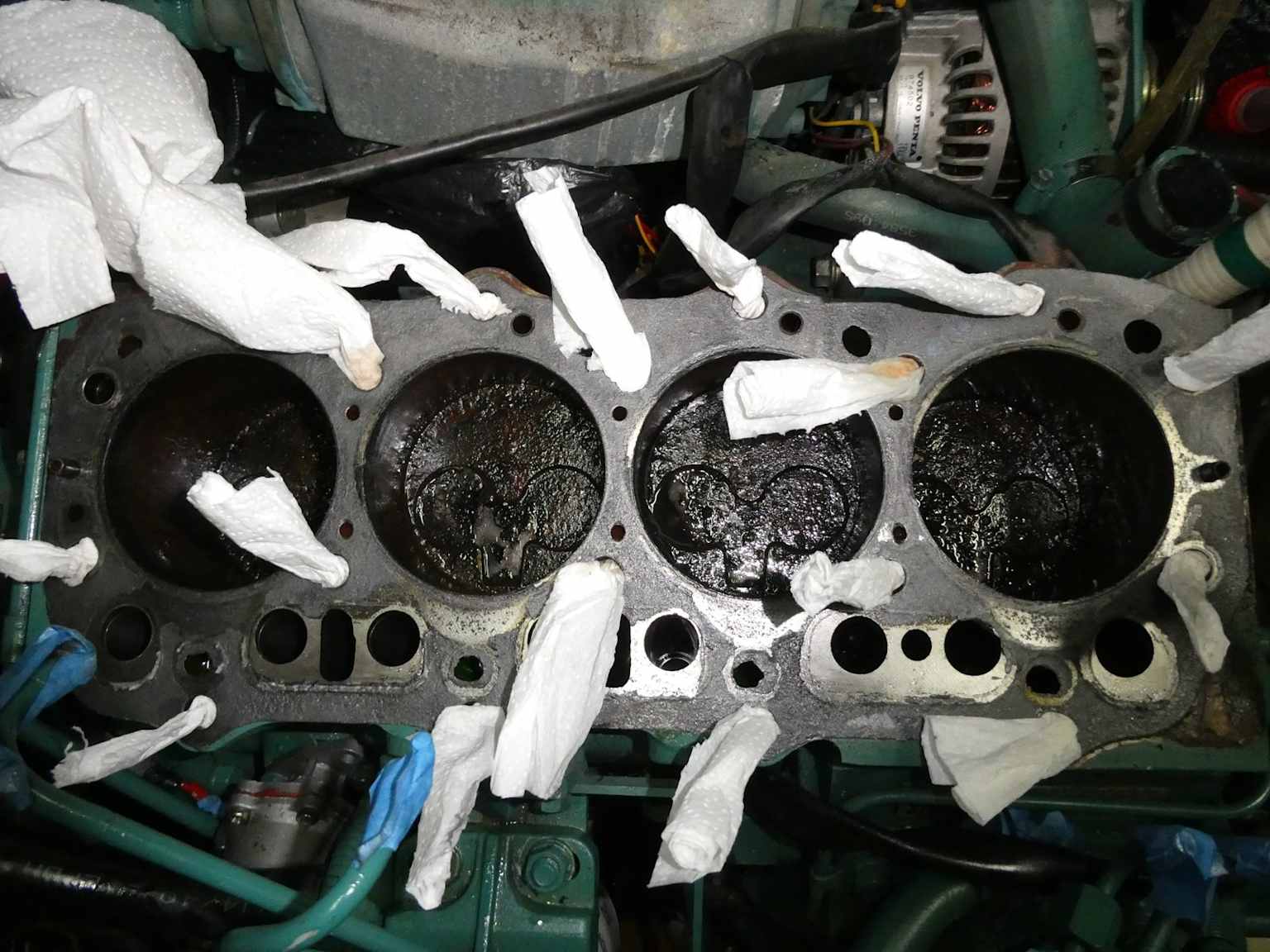 Internal view of a hydrolocked engine with visible piston damage and paper towels in ports during repair