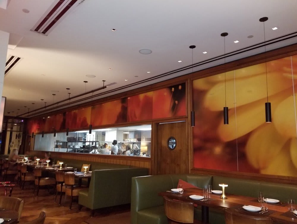 Interior view of BLT Steak in Honolulu showcasing its warm and elegant ambiance with an open kitchen and stylish decor