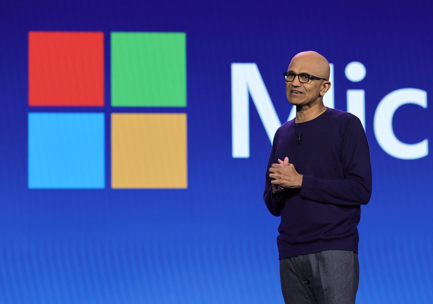 Microsoft CEO presenting during a corporate event with the Microsoft logo in the background