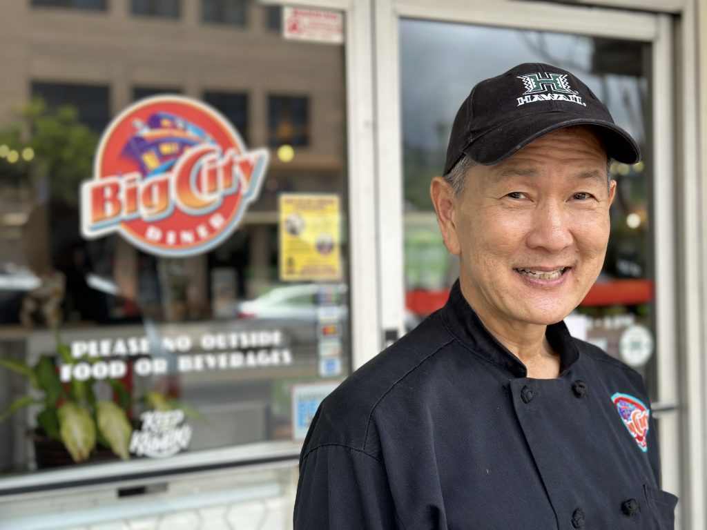 Staff member outside Big City Diner in Hawaii wearing professional chef attire reflecting authentic local restaurant culture