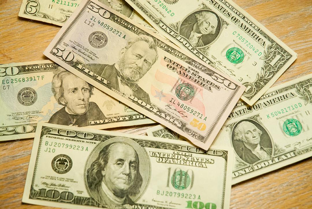 Various denominations of United States dollar bills displayed on a wooden surface, illustrating the familiar physical form of the US currency.