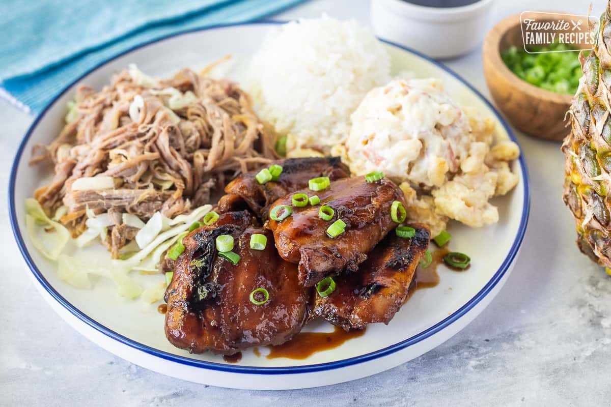 A traditional Hawaiian plate lunch featuring kalua pork, teriyaki chicken, white rice, and macaroni salad