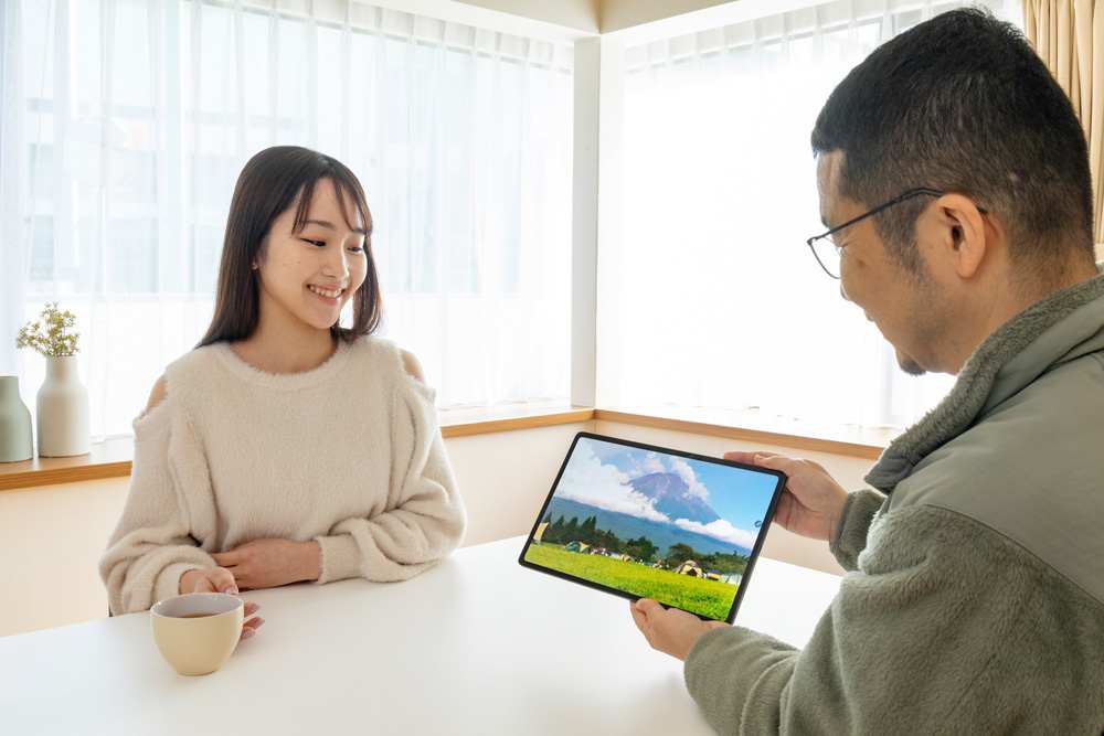 明るいリビングルームで、大画面タブレットでビデオコンテンツを共有する家族